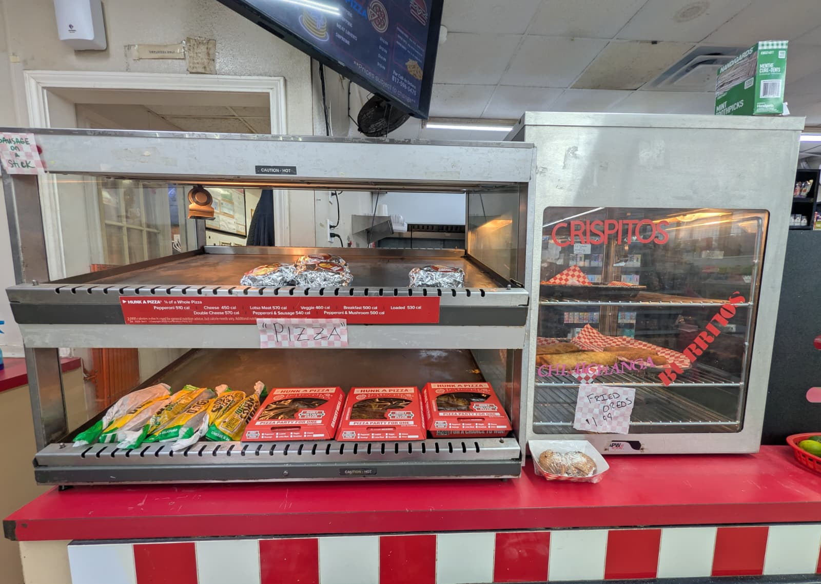 Hot case with pizza slices, burritos, and crispitos